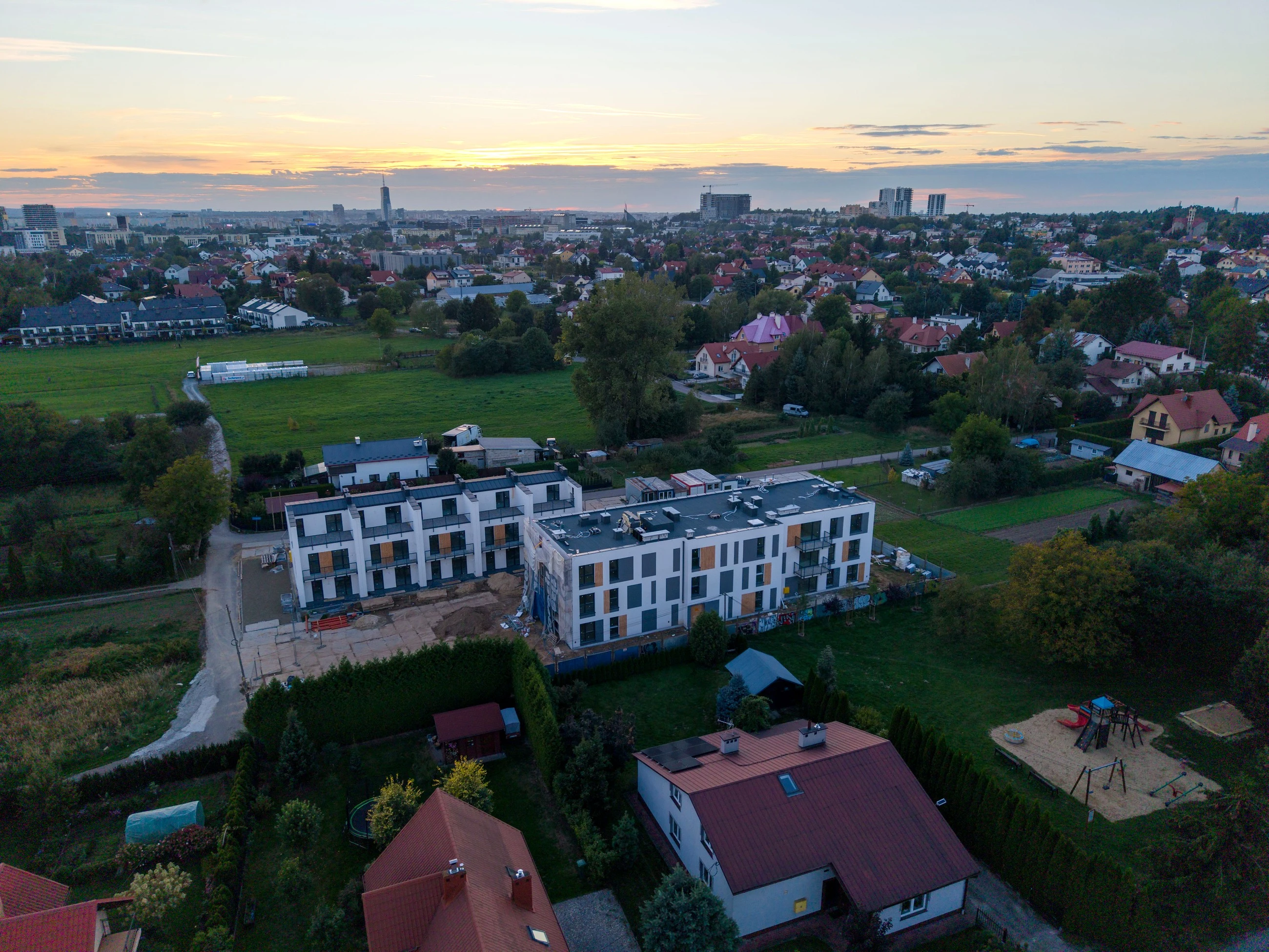 Osiedle Odnowiciela w Rzeszowie z drona o zachodzie słońca, oba etapy na tle domów jednorodzinnych i panoramy centrum, 16 września 2026
