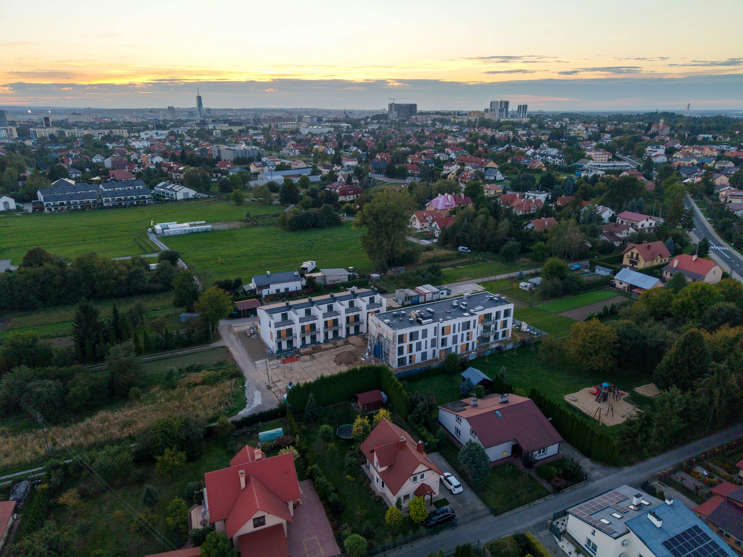 Panorama Wilkowyi z drona: Osiedle Odnowiciela I i II, łąki, domy jednorodzinne i wieżowce centrum Rzeszowa na horyzoncie, 16 września 2026